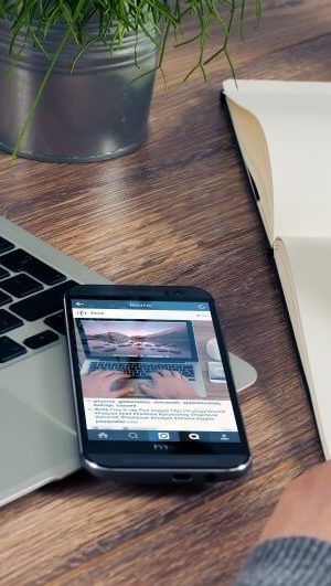 woman-sitting-at-table-writing-in-notepad-with-laptop-and-mobile-phone-on-wooden-table woman-sitting-at-table-writing-in-notepad-with-laptop-and-mobile-phone-on-wooden-table